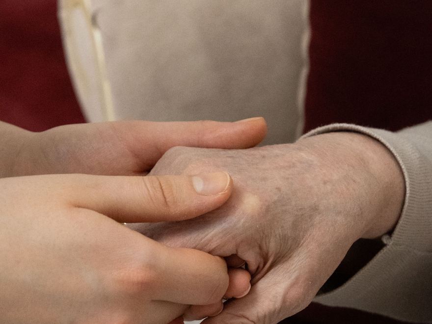 Eine jüngere Hand hält die Hand eines älteren Menschen.