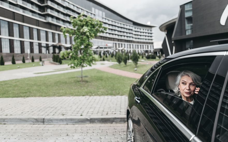 Eine ältere Dame telefoniert im Auto.
