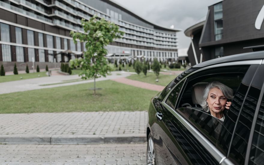 Eine ältere Dame telefoniert im Auto.